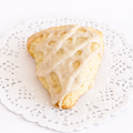 A small, triangular scone with an airy, crumbling texture, drizzled with a white glaze flecked with vanilla beans.